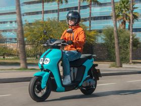 Mujer motorista en scooter azul